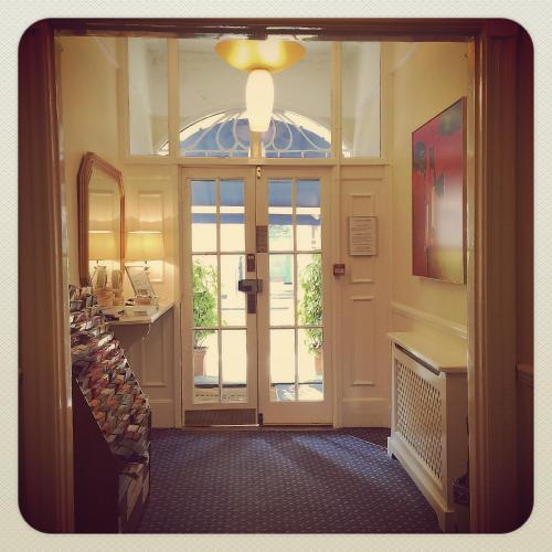 a hallway with a glass door and a mirror at Thanet Hotel in London