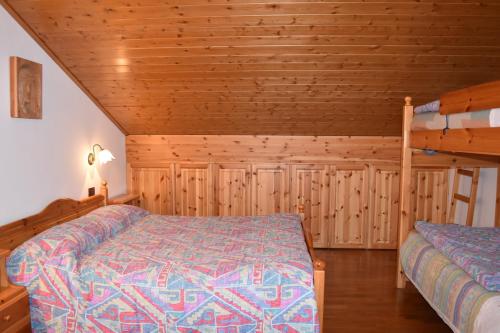 a bedroom with two beds and wooden walls at Appartamento Sellaronda in Arabba