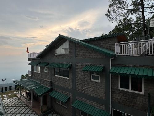 a building with green awnings on the side of it at ELIVAAS Ivory Ridge 9 BHK Cliffside Villa with Picturesque View in Kasauli