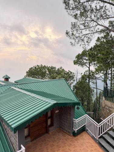 a house with a green roof and stairs at ELIVAAS Ivory Ridge 9 BHK Cliffside Villa with Picturesque View in Kasauli