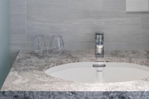 a bathroom sink with two wine glasses on it at CHECK inn Express Taichung Fuxing in Taichung