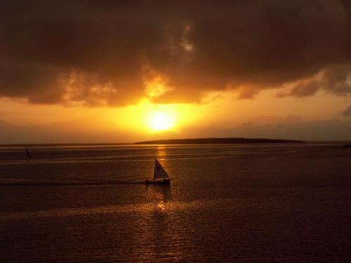 a boat in the water with a sunset in the background at Coco Villa in Mahébourg