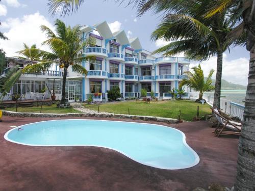 a resort with a swimming pool in front of a building at Coco Villa in Mahébourg