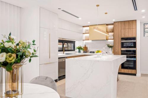 a white kitchen with a white counter and a vase of flowers at Family-friendly entire Lux 4BR Home 2 parking in Miranda