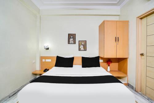 a bedroom with a large white bed and a wooden cabinet at Super Townhouse Durgapura formerly Gumaan Heritage in Jaipur