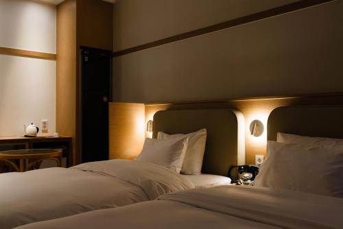 a bedroom with two beds with white sheets and lights at Yangju Hotel Ippda in Yangju