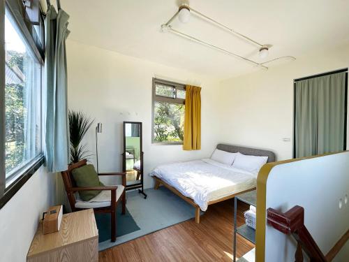a bedroom with a bed and a chair and a window at Beacon Yard Jiufen 九份拾光書院 in Jiufen