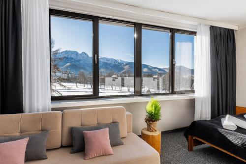 a living room with a couch and large windows at Hotel Helios 300m od Krupówek nowy BASEN od 12 lipca in Zakopane