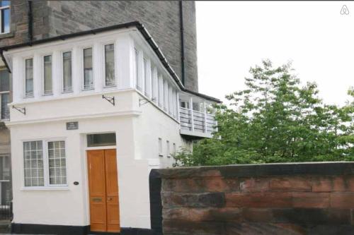 ein weißes Haus mit einer roten Tür und einer Ziegelwand in der Unterkunft Heritage City - The Auld Pottery in Edinburgh