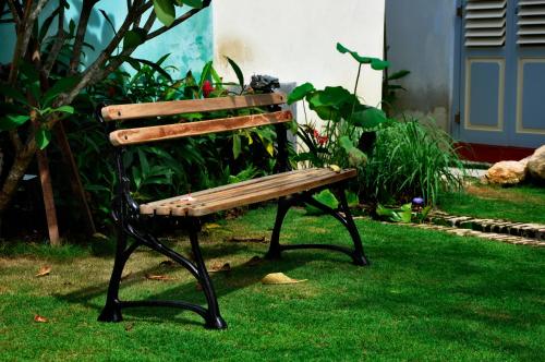 a wooden bench sitting on the grass in a yard at 23 Love Lane Hotel in George Town