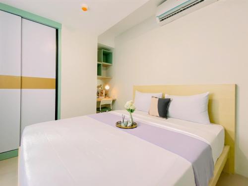 a bedroom with a white bed with a vase on it at Modern Look 2BR Apartment at Anwa Residence By Travelio in Tangerang