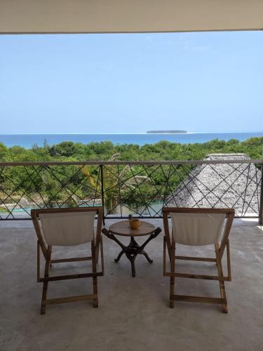 two chairs and a table on a balcony at Alcyone Residence - Ocean View Villa in Muyuni