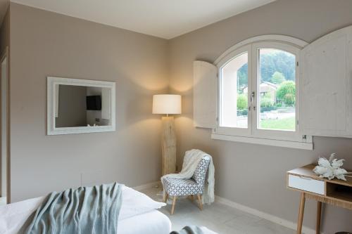 a bedroom with a bed and a chair and a window at Bianco Hotel in Primaluna