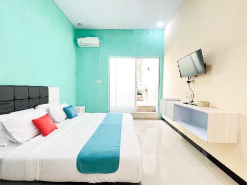 a bedroom with a large bed and a television at Sans Borobudur Homestay Banyuwangi in Banyuwangi