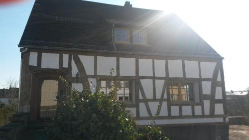 a black and white house with the sun shining on it at Historische Wassermühle in Birgel