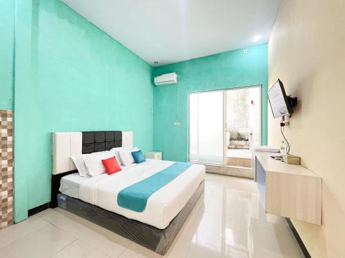 a bedroom with a bed and a blue wall at Sans Borobudur Homestay Banyuwangi in Banyuwangi