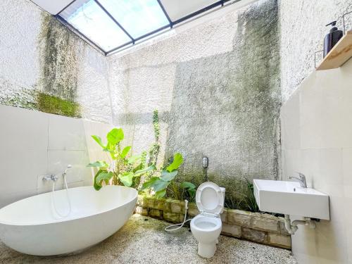a bathroom with a tub and a toilet and a sink at Sans Borobudur Homestay Banyuwangi in Banyuwangi