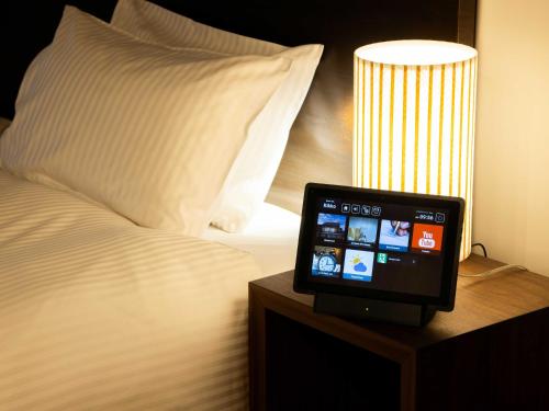 a tablet computer sitting on a table next to a bed at Auberge Homachi Mikuniminato in Sakai