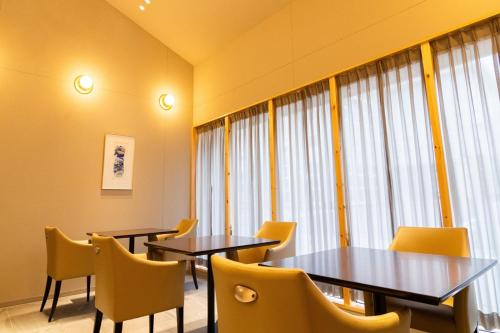 a restaurant with two tables and yellow chairs at Auberge Homachi Mikuniminato in Sakai