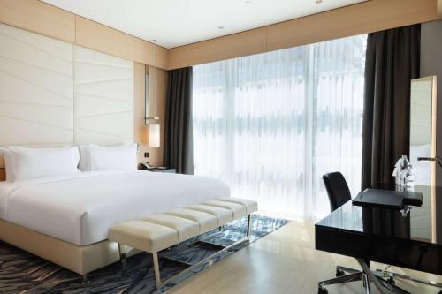 a bedroom with a large white bed and a desk at Wyndham Grand Istanbul Levent Hotel & Conference Center in Istanbul