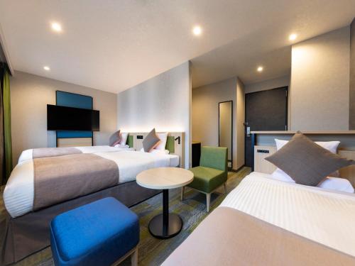 a hotel room with two beds and a table and chairs at HOTEL MYSTAYS Miyazaki in Miyazaki