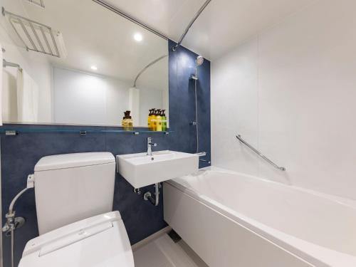 a bathroom with a toilet and a sink and a bath tub at HOTEL MYSTAYS Miyazaki in Miyazaki