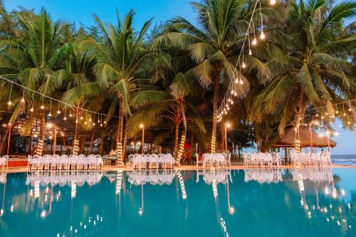 a pool with chairs and palm trees and lights at Cam Binh Resort Lagi in La Gi