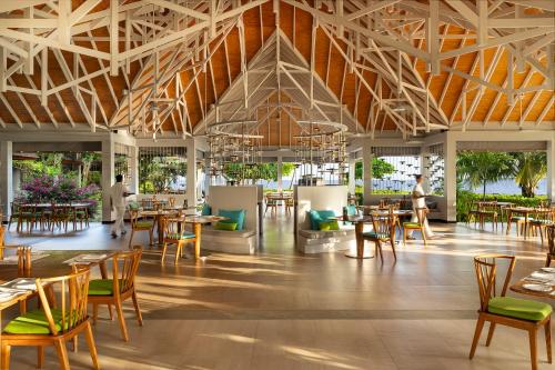 a restaurant with wooden tables and chairs and a large ceiling at Dhigali Maldives - A Premium All-Inclusive Resort in Raa Atoll