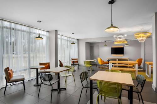 a cafeteria with tables and chairs and a tv at Spark by Hilton Richardson Dallas in Richardson