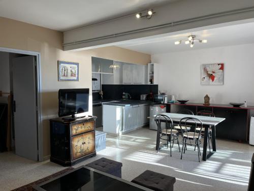 Il comprend une cuisine avec une table et des chaises ainsi qu'une télévision. dans l'établissement le mediterranee vasapolli, à Fréjus