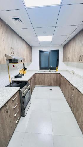 a large kitchen with wooden cabinets and a ceiling at Spacious & Stylish 3-Bedroom Home in a Prime Location in Dubai