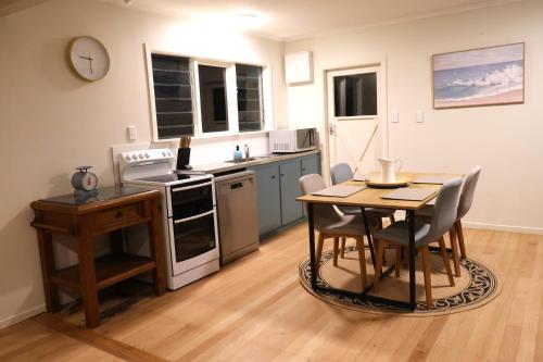 una cucina con un tavolo e sedie in una stanza di Cozy Family Home 10min to Airport and Pet friendly ad Auckland