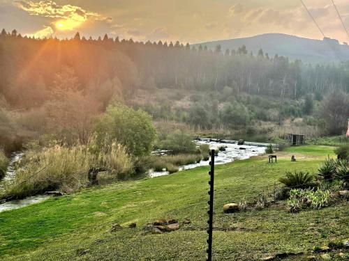 a fence in a field with a river and mountains at Misty River in Lions River