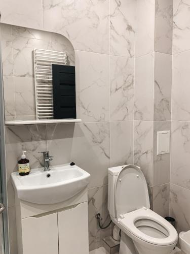 a white bathroom with a toilet and a sink at Apartments Domovik Стильна квартира, Миру 11 c кв 2 in Mukacheve
