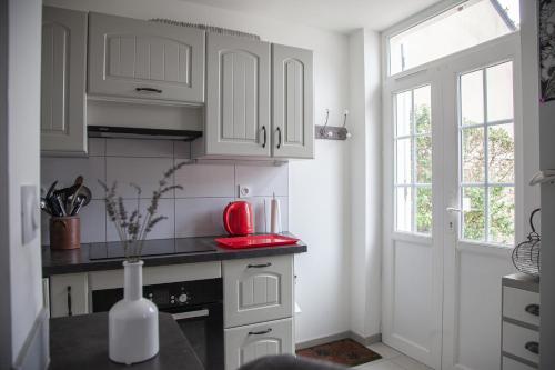 une cuisine avec des armoires blanches et un appareil rouge dans l'établissement Rez de chaussée, place du marché, plage à pied, à Pornichet