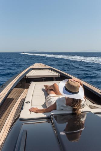 a woman laying on the back of a boat on the water at Virtu on the Hill in Stelida