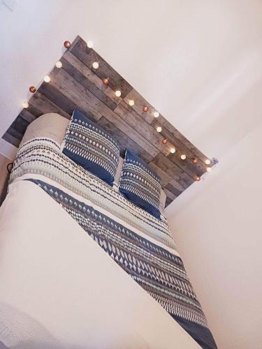 - un lit avec des oreillers bleus et des lumières au plafond dans l'établissement Maisonette Cap d 'Agde, au Cap d'Agde