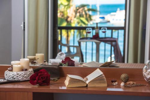 a table with an open book with candles and roses at Onar Corfu Aparts & Studios in Ýpsos