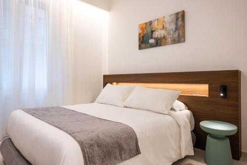 a bedroom with a white bed with a wooden headboard at Nora's Suites in Palermo