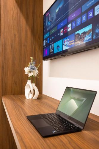 a laptop computer sitting on a wooden desk with a tv at Nora's Suites in Palermo