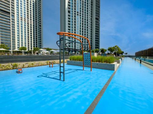 a swimming pool with a playground in front of tall buildings at Royal Vista at Downtown Views II - Downtown Dubai City Views - Brand New Luxury 2BR Apartment in Dubai