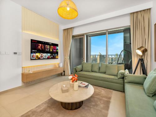 a living room with a green couch and a table at Royal Vista at Downtown Views II - Downtown Dubai City Views - Brand New Luxury 2BR Apartment in Dubai