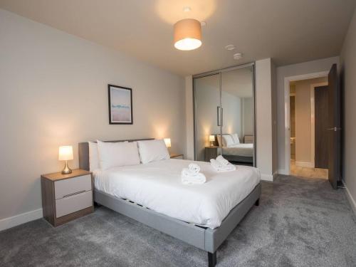 a bedroom with a large bed with two towels on it at Sophisticated Apartment with Parking Central Slough in Slough