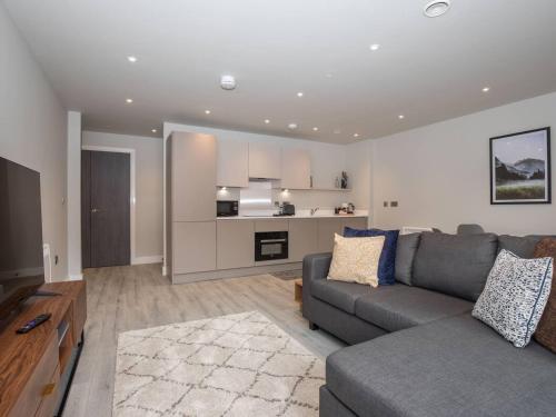 a living room with a gray couch and a kitchen at Sophisticated Apartment with Parking Central Slough in Slough