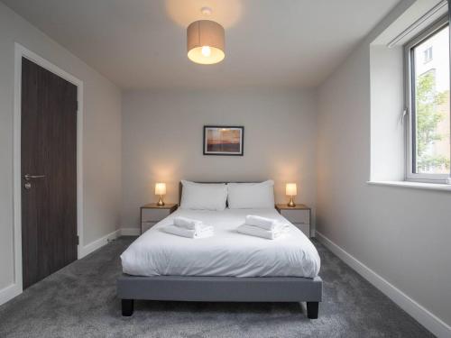 a bedroom with a bed with two night stands and a window at Sophisticated Apartment with Parking Central Slough in Slough