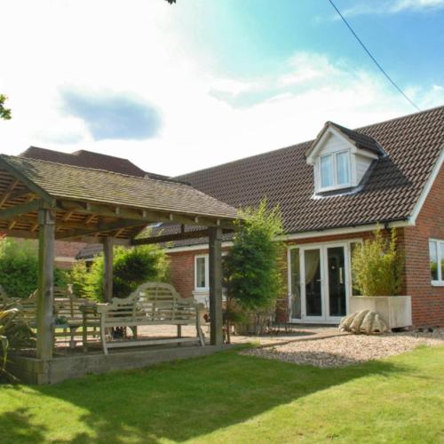 a house with a wooden pergola and a bench at Harford en-suite Rooms in Lymington