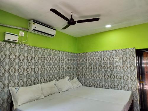 a bed in a room with a ceiling fan at Hotel Grand Arputha in Velankanni