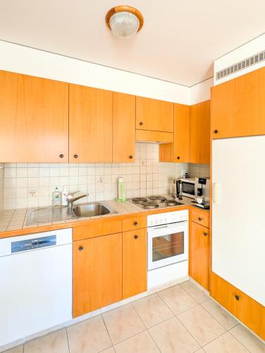 a kitchen with wooden cabinets and a sink at Ovronnaz vue imprenable, terrasse & accès bains in Ovronnaz