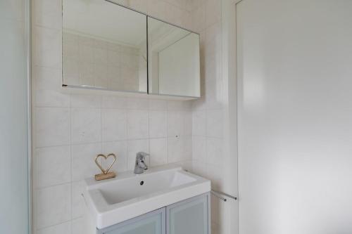 a white bathroom with a sink and a mirror at Graspieper I Vrijstaand Huisje met Brede Tuin in Zwiggelte