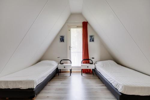 two beds in a room with a window at Graspieper I Vrijstaand Huisje met Brede Tuin in Zwiggelte